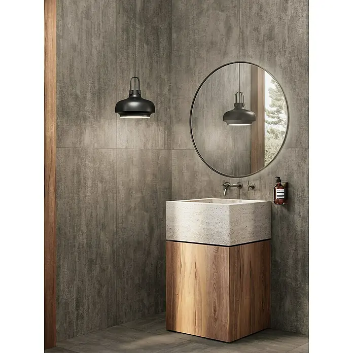 Atlas Concorde Solution Yorkshire Feinsteinzeugfliese Midnight - 60 x 120 cm, Anthrazit, Matt - Modernes Badezimmer-Interieur mit hölzernem Waschtischunterschrank, quadratischem Steinwaschbecken, rundem Spiegel und minimalistischer Hängelampe.