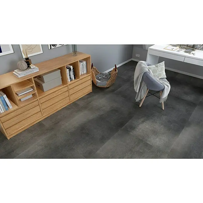 Feinsteinzeugfliese One - 74,5 x 74,5 cm, Anthrazit, Matt - Einladender Raum mit einem Holzschrank, einem Korb und einem Stuhl mit einer Decke, der eine gemütliche Atmosphäre schafft.