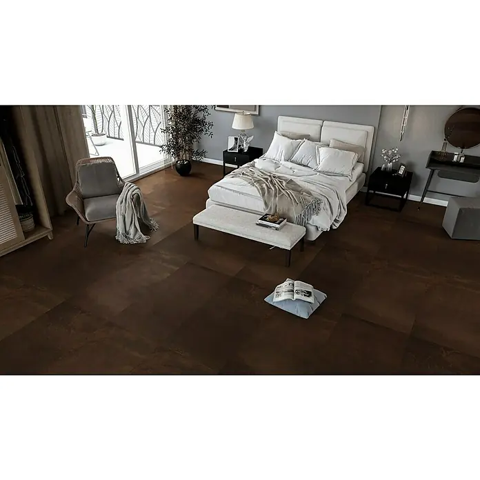 Feinsteinzeugfliese Metallo Rame - 60 x 120 cm, Kupfer, Matt - Schlafzimmer mit einem großen Bett, einem Sessel und einem Hocker. Der Boden ist mit dunklen Fliesen ausgelegt, die eine warme und einladende Atmosphäre schaffen.