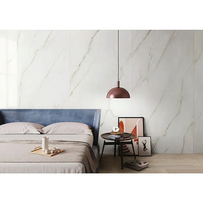 Feinsteinzeugfliese Calacatta Africa - 60 x 120 cm, Weiß, Glänzend - Schlafzimmer mit einem Bett mit blauem Kopfteil und einer Marmorwand im Hintergrund, die dem Raum eine elegante Note verleiht.