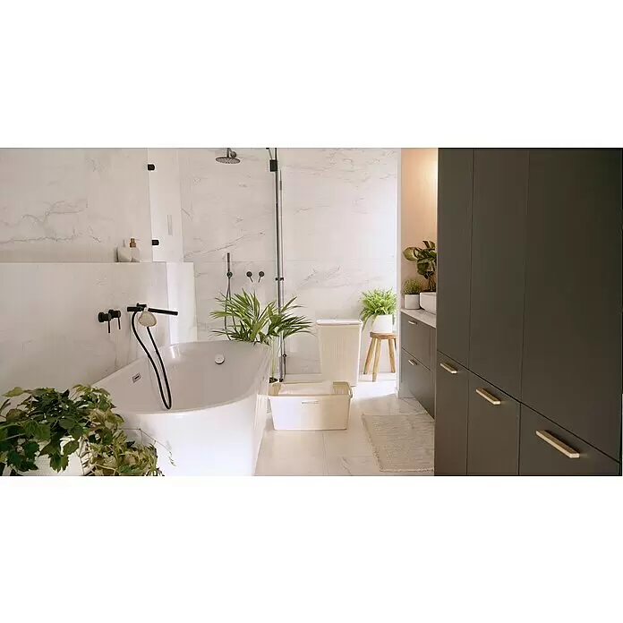 Curver Wäschekorb Jute - L x B x H: 59,4 x 39,4 x 25,6 cm, Cremeweiß - Ein modernes, helles Badezimmer mit freistehender weißer Badewanne, Marmorfliesen, schwarzen Armaturen und Grünpflanzen. Dunkelgraue Schränke runden den Look ab.
