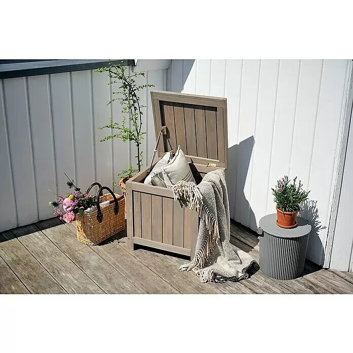 Butenkist Garten-Aufbewahrungsbox HILLE - Warm Grey, Holz - Graue Holzkiste für den Außenbereich auf einer Terrasse, geöffnet, mit Kissen und einer Decke.