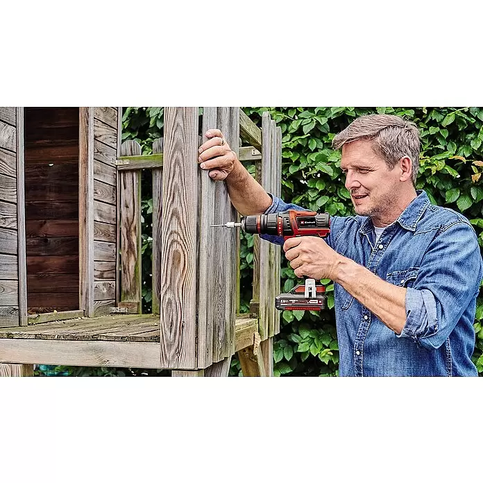 Einhell Power X-Change 18V Akku-Bohrschrauber TE-CD 18/45 3X-Li +22 - 18 V, 1 Akku, 2 Ah - Rote und schwarze Einhell Akku-Bohrmaschine, von einem Mann in eine Holzkonstruktion bohrend.