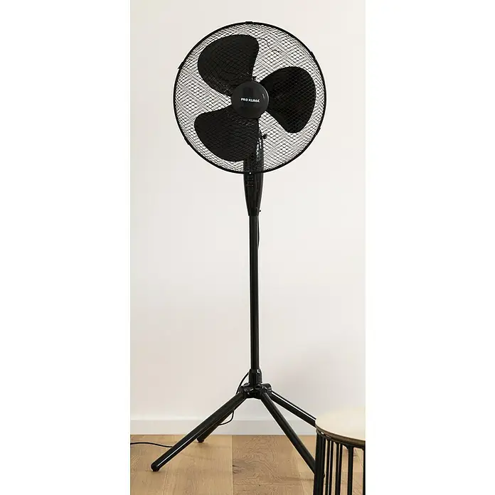 Voltomat Standventilator - Schwarz, 40 cm, 125 cm - Ein schwarzer Pro Klima Standventilator mit drei Flügeln, der auf einem Holzboden vor einer weißen Wand steht, bietet kühle Luft an warmen Tagen.