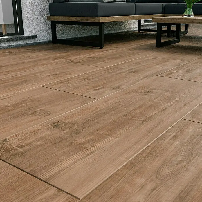 Esterno 20 T by Palazzo Terrassenfliese Harmonie - 40 x 120 x 2 cm, Fichte, Matt - Nahaufnahme von Holzfliesen mit einem Sofabereich im Hintergrund, der die natürliche Schönheit und Textur des Materials hervorhebt.