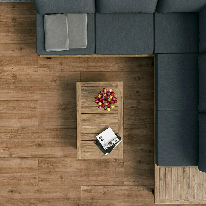 Esterno 20 T by Palazzo Terrassenfliese Harmonie - 40 x 120 x 2 cm, Fichte, Matt - Draufsicht auf ein Wohnzimmer mit einem grauen Sofa, Holztisch, Blumen und Büchern. Das Parkett verleiht dem Raum Wärme und Eleganz.