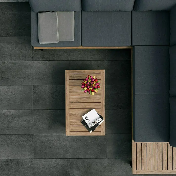 Esterno 20 T by Palazzo Terrassenfliese Basalt - 40 x 120 x 2 cm, Schwarz, Matt - Draufsicht auf eine elegante Sitzecke im Freien mit modularem Sofa, Holztisch, Blumen und Zeitschriften auf dunklem Fliesenboden.