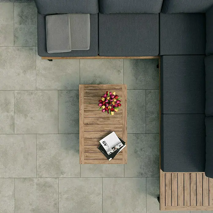 Cersanit Terrassenfliese Metropolis - 59,3 x 59,3 x 2 cm, Light Grey, Matt - Blick von oben auf eine graue Loungegarnitur mit Holztisch, dekoriert mit Blumen und Zeitschriften, die eine stilvolle Entspannungsoase zeigen.