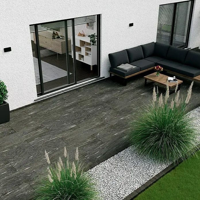 Marazzi Terrassenfliese Esterno 20T Davos - 40 x 120 x 2 cm, Anthrazit, Matt - Elegante dunkle Terrassenfliesen mit stilvollem Gartenmöbel-Set und dekorativen Gräsern für eine moderne Außenbereichgestaltung.