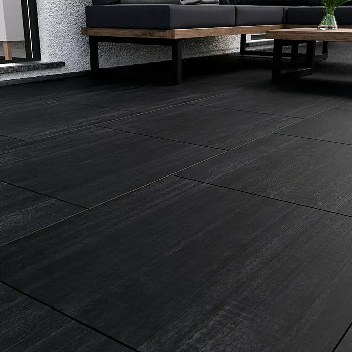 Terrassenfliese Garden Black Struktur - 59,7 x 59,7 x 2 cm, Schwarz, Matt - Schwarze Fliesen mit Holzmaserung verlegen eine Terrasse mit einer stilvollen Loungegarnitur.
