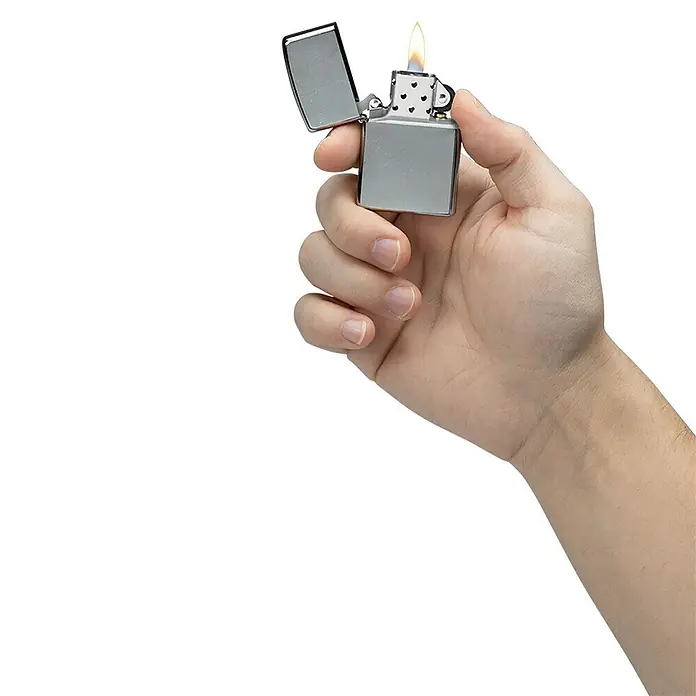 Zippo Sturmfeuerzeug Classic Street Chrome™ - Ohne - Nahaufnahme einer Hand, die ein brennendes Zippo-Feuerzeug hält, dessen metallisches Gehäuse und Flamme im schwarzen Hintergrund gut zur Geltung kommen.