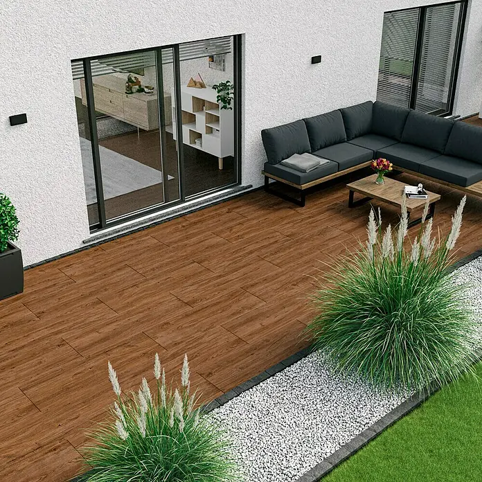 Marazzi Terrassenfliese Esterno 20T Woodliving Scuro - 40 x 120 x 2 cm, Braun, Matt - Außenansicht mit Terrassendielen in Holzoptik, grauem Sofa, Holztisch und Deko. Die Dielen verleihen dem Außenbereich Wärme und Eleganz.