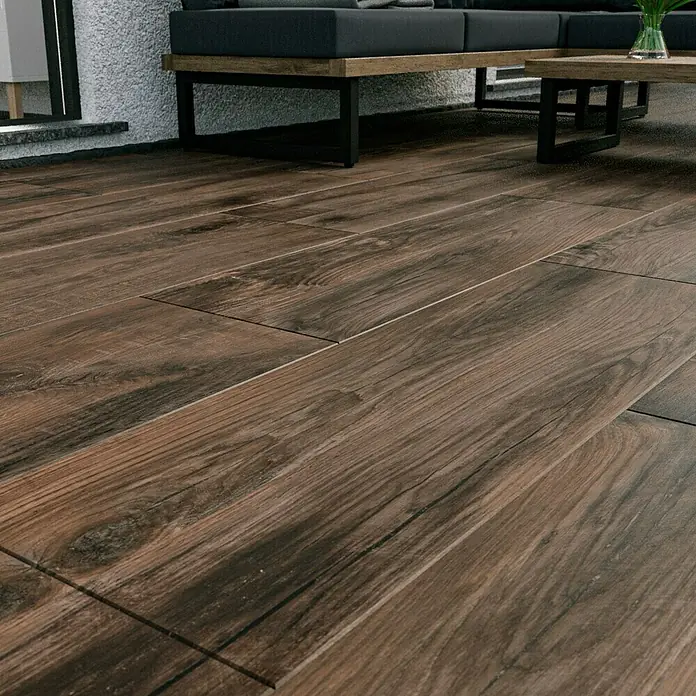 Marazzi Terrassenfliese Esterno 20T Trevermade - 40 x 120 x 2 cm, Zeder, Matt - Nahaufnahme von Holzfußbodenfliesen, die eine warme und einladende Atmosphäre schaffen. Möbel sind im Hintergrund zu sehen.