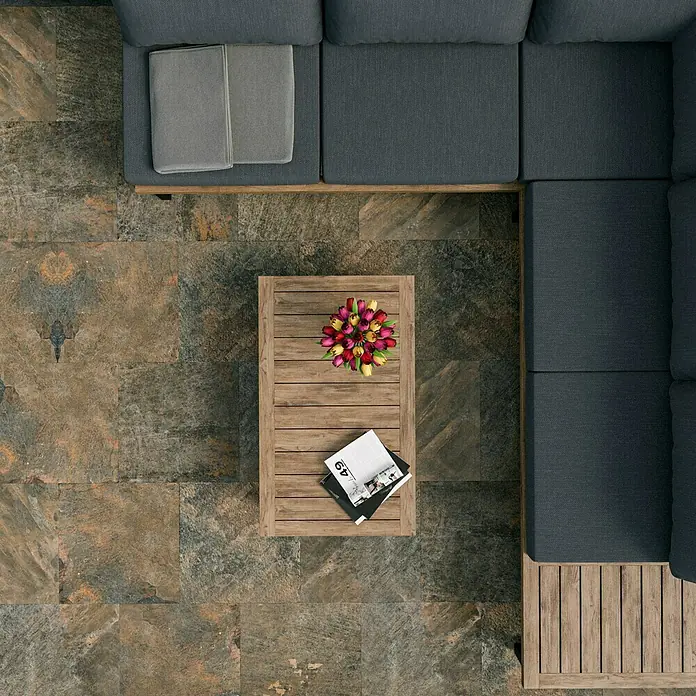 Marazzi Terrassenfliese Esterno 20T Rocking Grey - 60 x 60 x 2 cm, Grau/Braun, Matt - Top-Ansicht eines grauen Loungesofas mit Holztisch, Blumenvase und Magazinen auf einem Steinfliesenboden. Ideal für Entspannung im Freien.