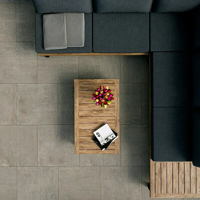 Terrassenfliese Garden Grey - 60 x 60 x 2 cm, Grau, Matt - Draufsicht auf ein modernes Outdoor-Wohnzimmer-Set mit modularem Sofa, Couchtisch mit Blumen und Zeitschriften auf Fliesenboden.