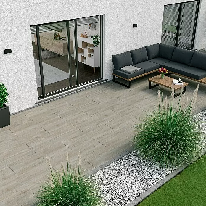 Marazzi Terrassenfliese Esterno 20T Woodliving Fumo - 40 x 120 x 2 cm, Beige, Matt - Eine Außenterrasse mit hellen Holzoptik-Bodenfliesen und einem dunkelgrauen Gartensofa mit Holzrahmen und Couchtisch.