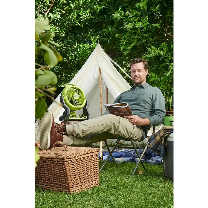 Ryobi ONE+ Akku-Ventilator RF18-0 - 18 V, Ohne Akku - Ein Mann entspannt beim Campen mit dem grünen Ryobi-Ventilator, der für eine angenehme Brise sorgt. Er genießt die Natur mit Komfort.