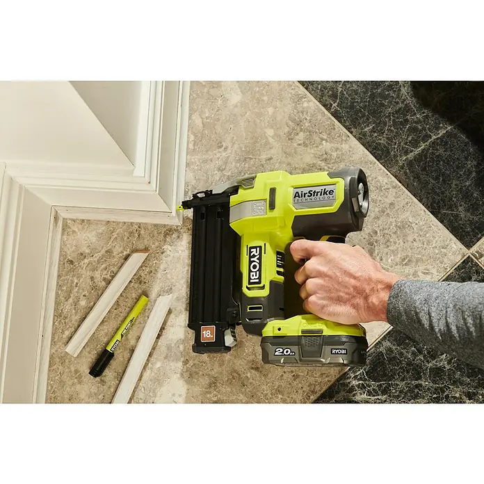 Ryobi ONE+ Akku-Nagler R18GN18-0 - 18 V, Ohne Akku, Länge Nagel: 15 mm - 50 mm - Nahaufnahme eines gelben Ryobi AirStrike Akku-Nagelgeräts beim Anbringen einer Zierleiste, das Werkzeug steht im Fokus.