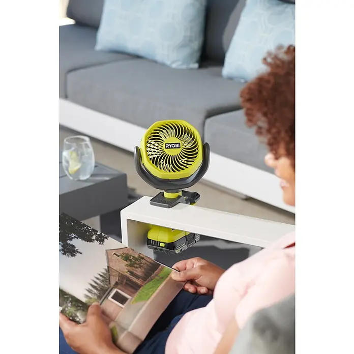 Ryobi ONE+ Akku-Ventilator RCF18-0 - 18 V, Ohne Akku - Ryobi ONE+ Akku-Ventilator auf einem Tisch, der für eine angenehme Brise im Freien sorgt, während man eine Zeitschrift liest.