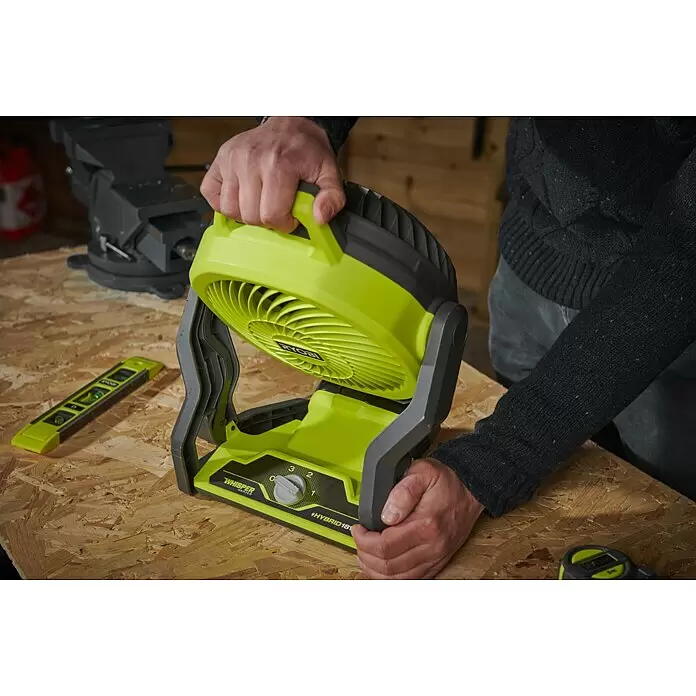 Ryobi ONE+ Akku-Ventilator RF18-0 - 18 V, Ohne Akku - Eine Person justiert einen grün-schwarzen tragbaren Ventilator auf einer Holzwerkbank, was seinen Einsatz in einer Werkstatt hervorhebt.