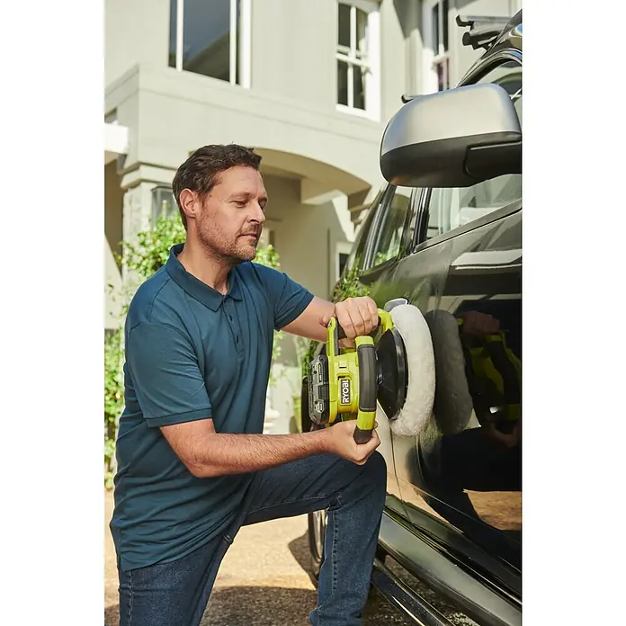 Ryobi ONE+ Polierrad RAK2BB - Passend für: RBP18250-0, 2 Stk., Durchmesser: 250 mm - Ein Mann benutzt einen Ryobi Polierer, um ein schwarzes Auto auf einer Einfahrt zu polieren. Er kniet während der Arbeit.