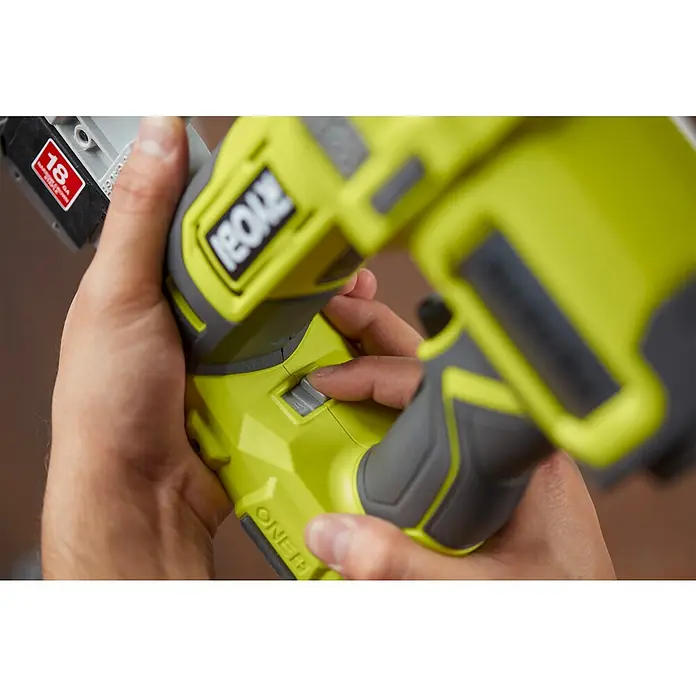 Ryobi ONE+ Akku-Nagler R18GN18-0 - 18 V, Ohne Akku, Länge Nagel: 15 mm - 50 mm - Nahaufnahme eines Ryobi ONE+ Akku-Nagelers, der von einer Hand bedient wird, um einen Schalter zu betätigen.