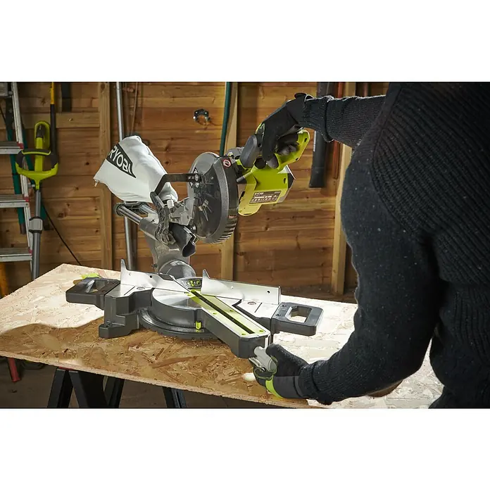 Ryobi ONE+ Akku-Kapp- & Gehrungssäge RMS18190-0 - 18 V, Ohne Akku, 3.600 U/min - Nahaufnahme einer Ryobi-Gehrungssäge in Aktion, bedient von einer Person mit Handschuhen in einer Werkstatt.