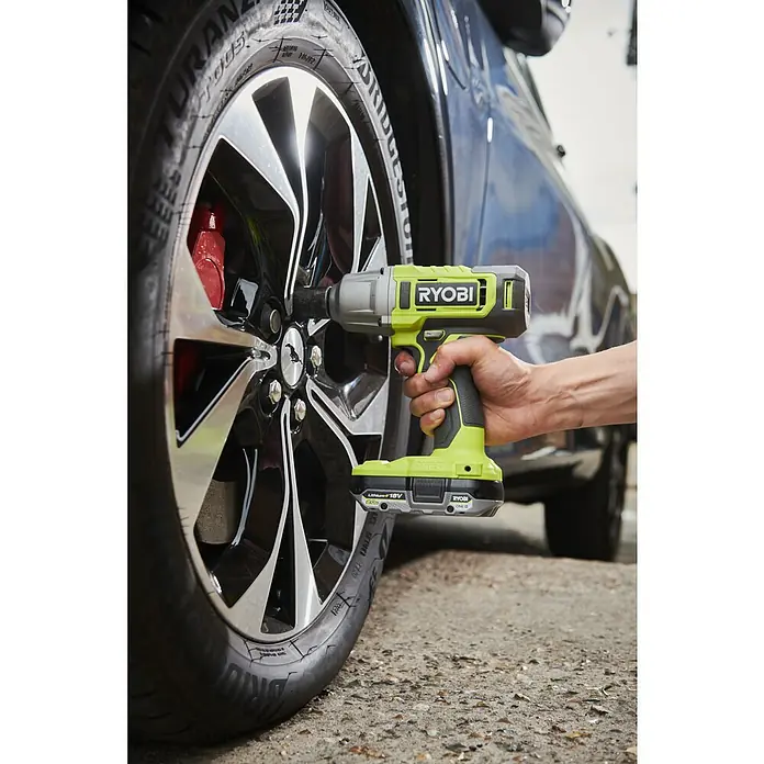 Ryobi ONE+ Akku-Schlagschrauber RIW18-0 - 18 V, Ohne Akku, 600 Nm - Ryobi Akku-Schlagschrauber im Einsatz beim Radwechsel. Das Werkzeug ist grün und schwarz und wird von einer Hand gehalten.