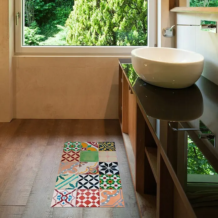 Alfombra de vinilo Croma Mosaic - Multicolor, 75 x 45 cm - Un primer plano de un baño con una alfombra colorida con patrones geométricos frente a un lavabo y una ventana con vistas a la vegetación.