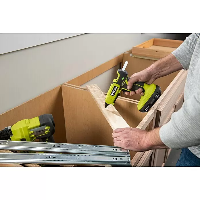 Ryobi ONE+ Akku-Heißklebepistole RGL18-0 - 18 V, Ohne Akku, 130 °C - 200 °C - Person klebt mit hellgrüner Ryobi Heißklebepistole eine Holzleiste bei der Schrankmontage.