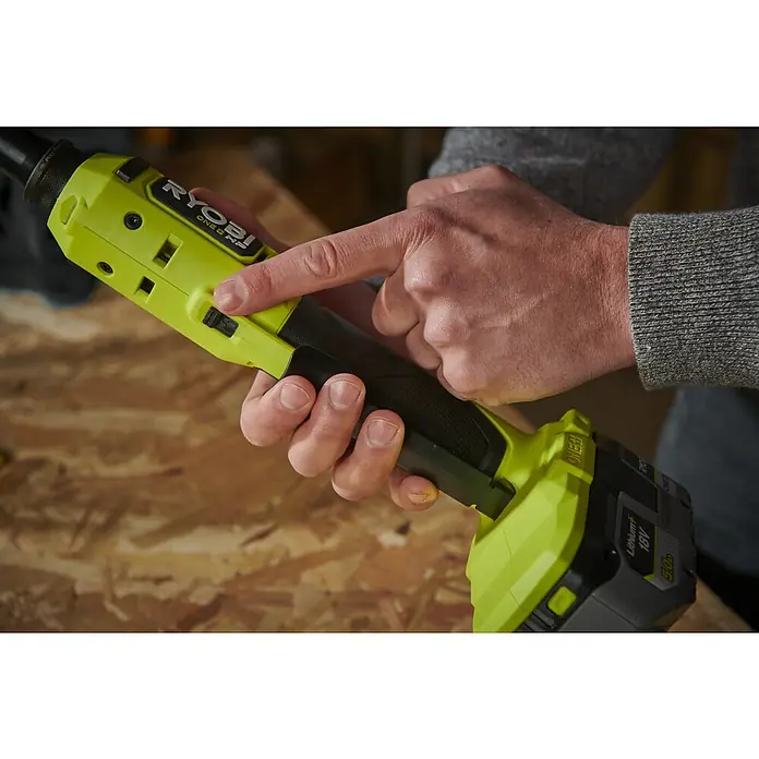 Ryobi ONE+HP Akku-Ratschenschrauber RRW1814X-0 - 18 V, Ohne Akku, ¼″, 60 Nm - Detailaufnahme eines gelb-schwarzen Ryobi ONE+ HP Werkzeugs, das von einer Hand bedient wird, mit Fokus auf den Schalter.