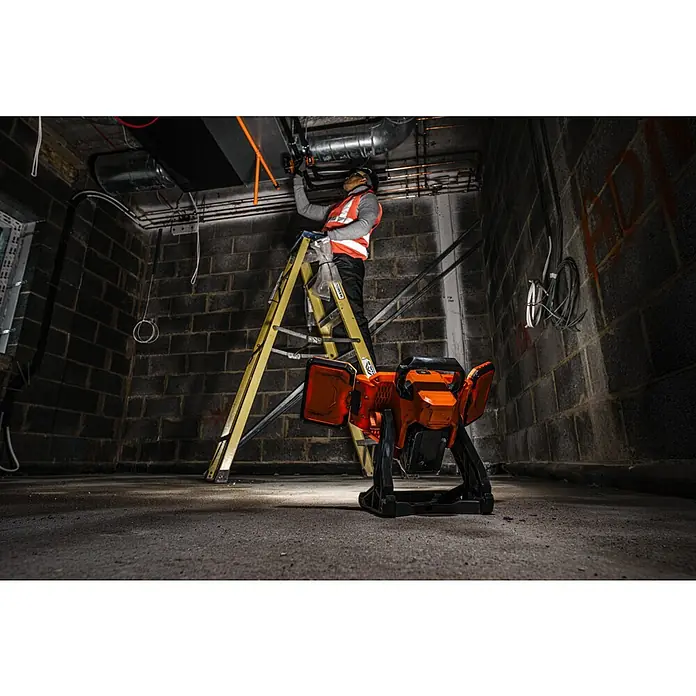 AEG Pro 18V LED-Arbeitsleuchte BLP18 - 18 V, 3.000 lm, Ohne Akku - Der Akku-LED-Baustrahler im Einsatz, während ein Arbeiter auf einer Leiter an der Decke arbeitet. Ideal für Baustellen und dunkle Arbeitsbereiche.