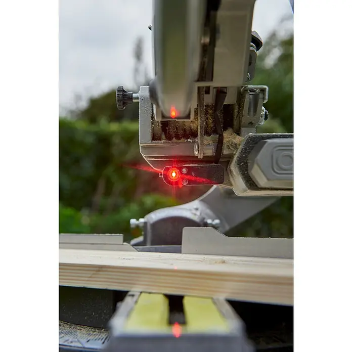 Ryobi ONE+ Akku-Kapp- & Gehrungssäge R18MS216-0 - 18 V, Li-Ionen, Ohne Akku, 0 U/min - 3.200 U/min - Nahaufnahme einer Kapp- und Gehrungssäge mit rotem Laser, die ein Holzbrett schneidet. Präzise Schnitte mit Werkzeug.