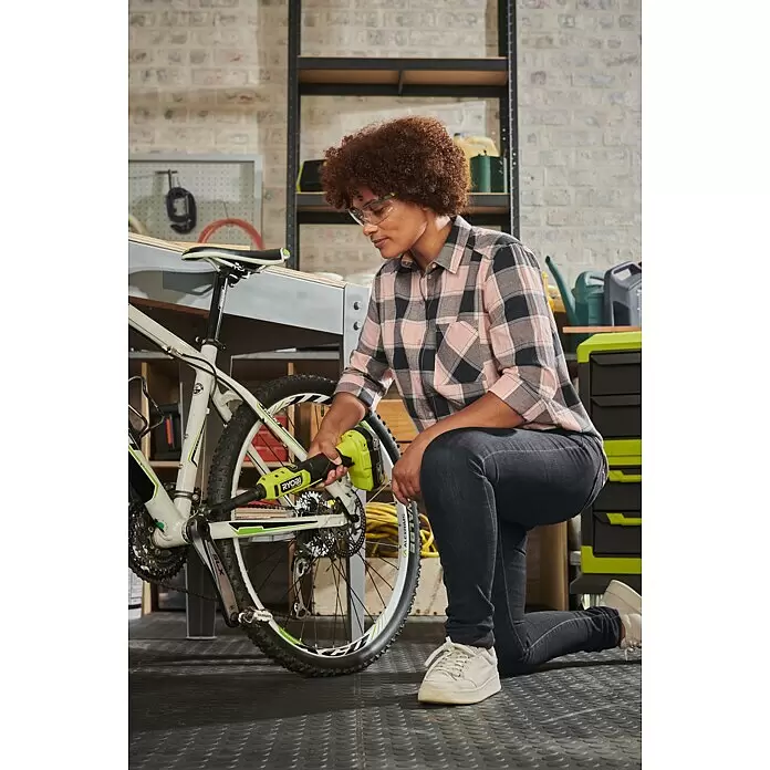 Ryobi ONE+HP Akku-Ratschenschrauber RRW1814X-0 - 18 V, Ohne Akku, ¼″, 60 Nm - Eine Person nutzt ein limettengrünes und schwarzes Elektrowerkzeug zur Fahrradwartung in einer Werkstatt.