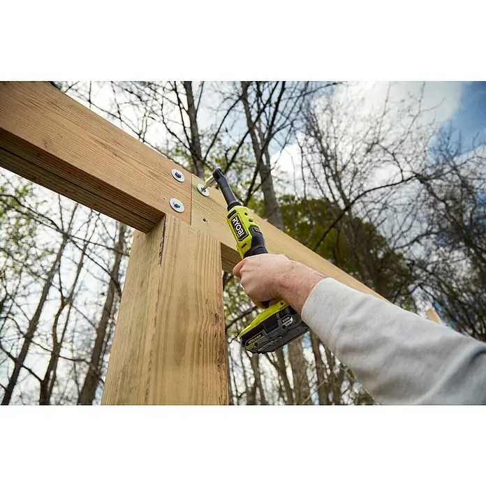 Ryobi ONE+HP Akku-Ratschenschrauber RRW1814X-0 - 18 V, Ohne Akku, ¼″, 60 Nm - Ein gelb-schwarzer Ryobi-Schlagschrauber befestigt mit Unterlegscheiben versehene Schrauben an einem Holzrahmen.