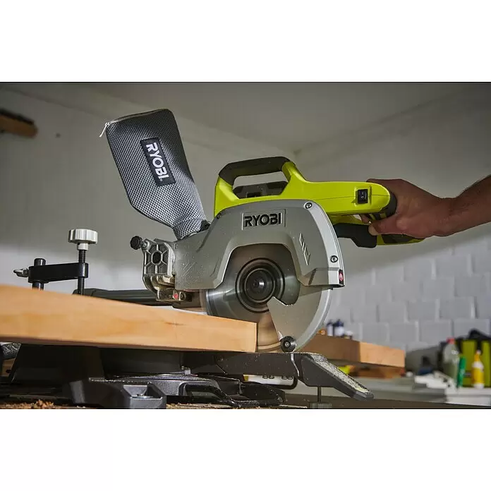 Ryobi ONE+ Akku-Kapp- & Gehrungssäge R18MS216-0 - 18 V, Li-Ionen, Ohne Akku, 0 U/min - 3.200 U/min - Eine grau-neongelbe Ryobi Kappsäge schneidet ein Holzbrett, von einer Hand bedient.