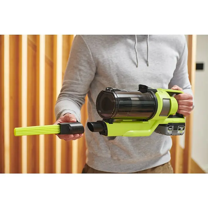 Ryobi ONE+HP Akku-Staubsauger RSV18X1-018 V, Ohne Akku, Behältervolumen: 0,8 l - Ein Mann präsentiert einen grünen Akku-Staubsauger mit einem Bürstenaufsatz in der Hand, ideal für die schnelle Reinigung zwischendurch.