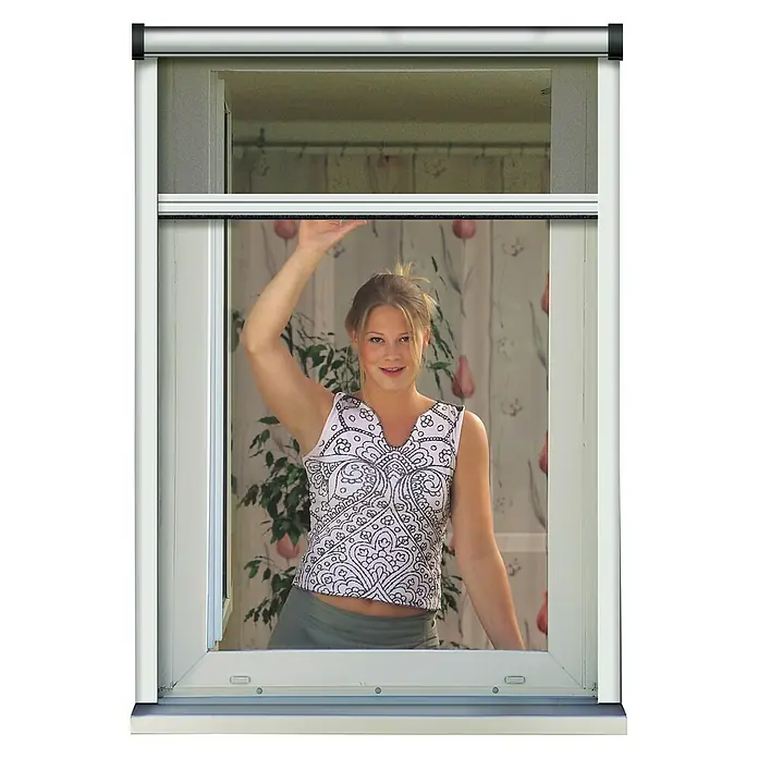 Schellenberg Insect System Mosquitera enrollable Basic - An x Al: 130 x 160 cm, Montaje de la mosquitera: Inserción, Color bastidor: Blanco - La imagen muestra un mosquitero enrollable en una ventana que oculta parcialmente a una mujer al fondo.