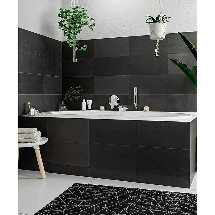 Hansgrohe Focus UP-Badewannenarmatur - Chrom, Glänzend - Ein elegantes Badezimmer mit einer stilvollen Badewanne, umgeben von dunklen Fliesen und grünen Pflanzen, die eine entspannende Atmosphäre schaffen.