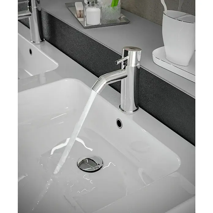 Grohe Essence New Waschtischarmatur S-Size - Höhe: 17,4 cm, Chrom, Glänzend - Nahaufnahme eines modernen Waschbeckens mit glänzendem Wasserhahn, aus dem Wasser fließt. Elegantes Baddesign mit zeitgemäßer Ästhetik.