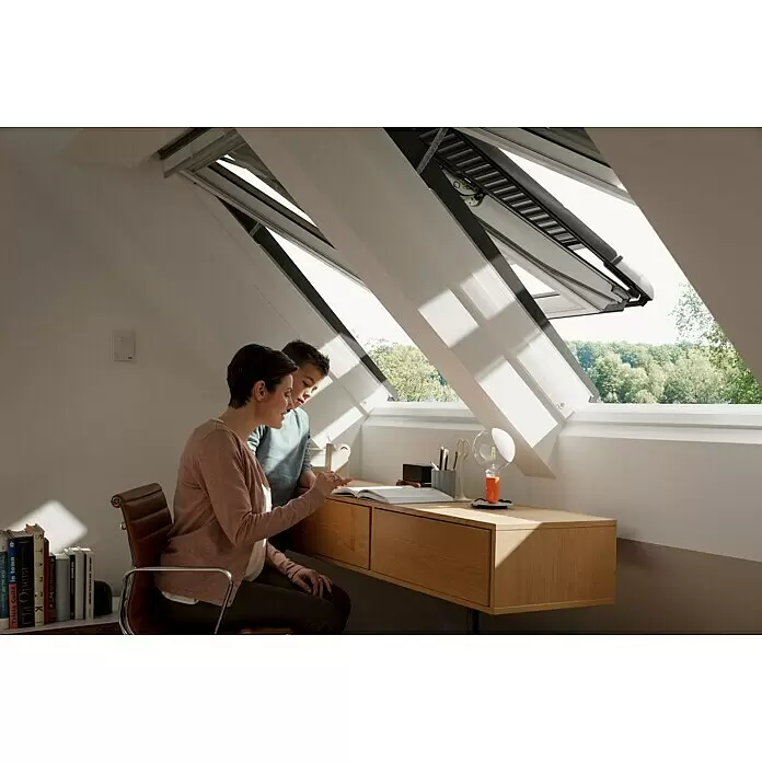 Velux App Control KIG 300 - Passend für: VELUX Solar- & Elektro-Produkte hergestellt seit 2007 - Helles Dachzimmer mit offenen Dachfenstern, einem Holzschreibtisch und zwei lesenden Personen. Ein Wandbedienfeld ist sichtbar.