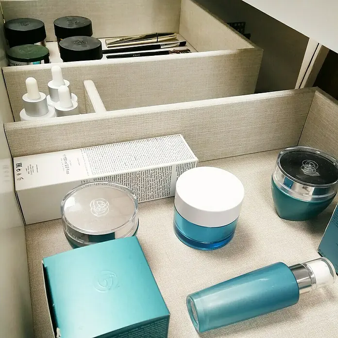 Artysan Conjunto de mueble de baño Yako - Ancho: 80 cm, Verde musgo, 3 pzs. - Un cajón con diversos productos de belleza, incluyendo cremas, sueros y cosméticos, con tonos azules, blancos y negros.