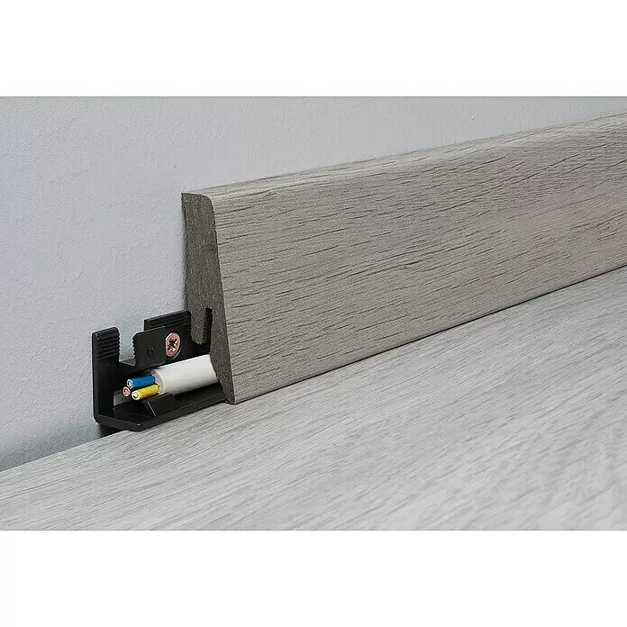 LOGOCLIC Aquaprotect Sockelleiste K58 C Tasso Oak - 2,6 m x 18 mm x 58 mm, HDF - Hellgraue, strukturierte Sockelleiste mit integriertem Kabelkanal, ein weißes Kabel darin sichtbar.