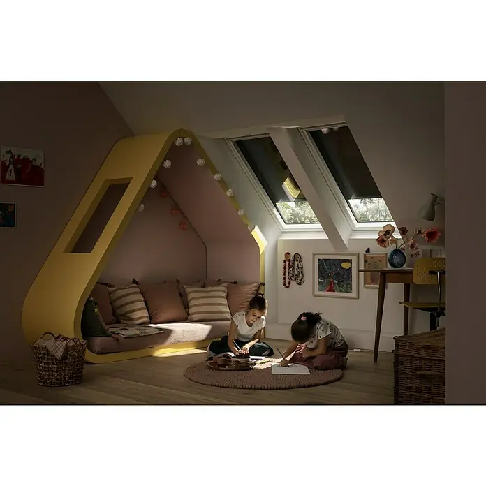 Velux Hitzeschutz-Markise Solar SSS - Passend für Fenstertyp: GGU, GGL, GPU, GPL, GHU, GHL, Passend für Fenstergröße: PK06, P06 - Zwei Kinder malen in einem gemütlichen Dachzimmer unter Dachfenstern, die Tageslicht hereinlassen. Niedlicher Spielbereich mit einladendem Tageslicht.