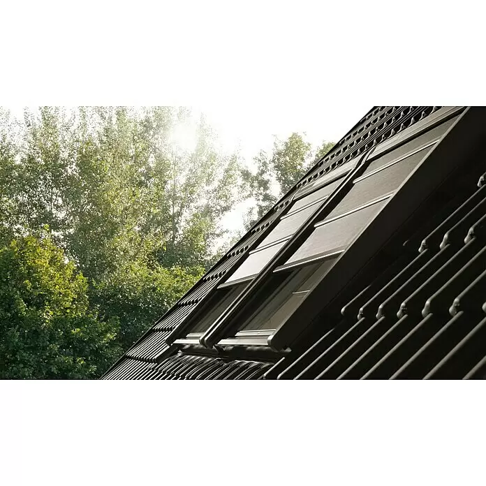Velux Hitzeschutz-Markise Solar SSS - Passend für Fenstertyp: GGU, GGL, GPU, GPL, GHU, GHL, Passend für Fenstergröße: FK06, F06 - Dunkle Außenjalousien an Dachfenstern auf einem Dach, mit hellem Sonnenlicht und Bäumen im Hintergrund.