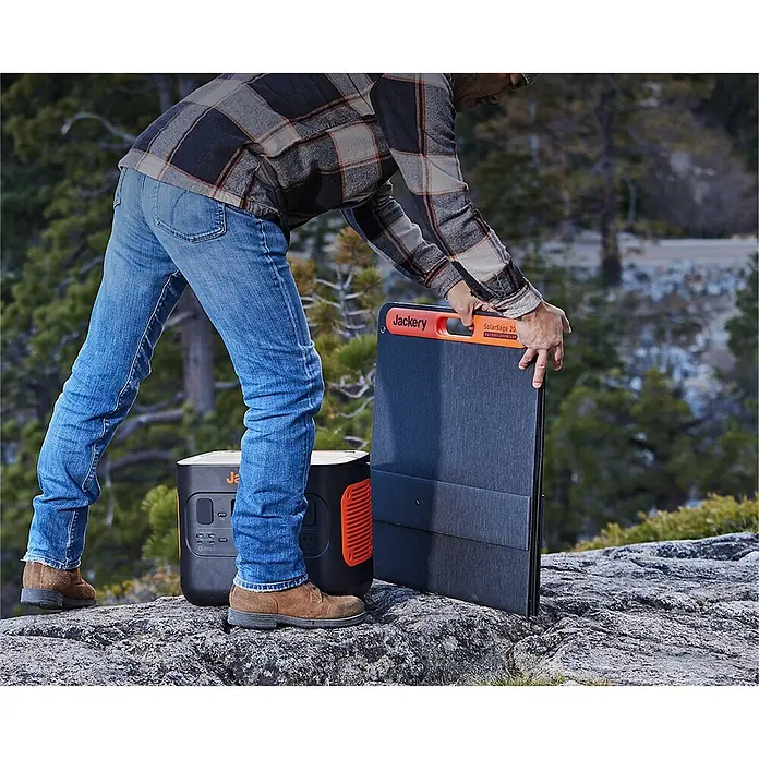 Jackery Panel solar Saga - 200 W, 235,5 x 54 cm - Una persona colocando un panel solar Jackery SolarSaga 20 junto a una estación de energía Jackery sobre una roca.
