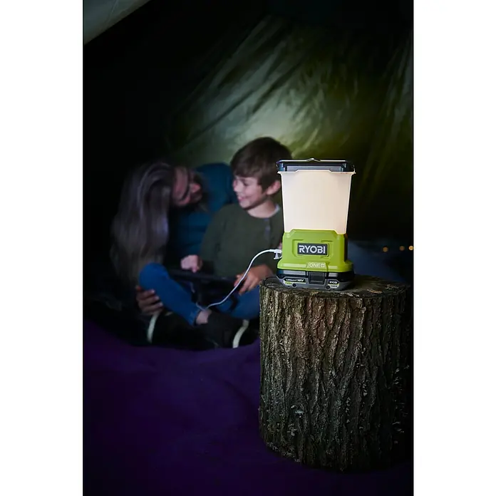 Ryobi ONE+ LED-Leuchte RLL18-0 - 850 lm, Ohne Akku - Ein RYOBI ONE+ Akku-Strahler beleuchtet ein Zelt, in dem ein Vater mit seinem Kind auf einem Tablet spielt.