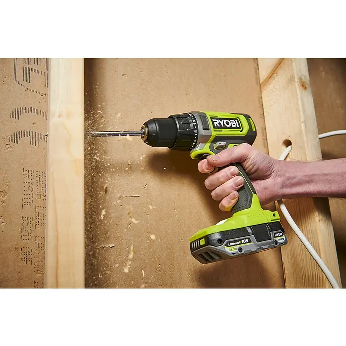 Ryobi ONE+ Akku-Bohrschrauber RDD18-0 - 18 V, Ohne Akku, 52 Nm - Nahaufnahme eines Ryobi-Akkuschraubers in Aktion, der ein Loch in eine Holzwand bohrt und Späne erzeugt.