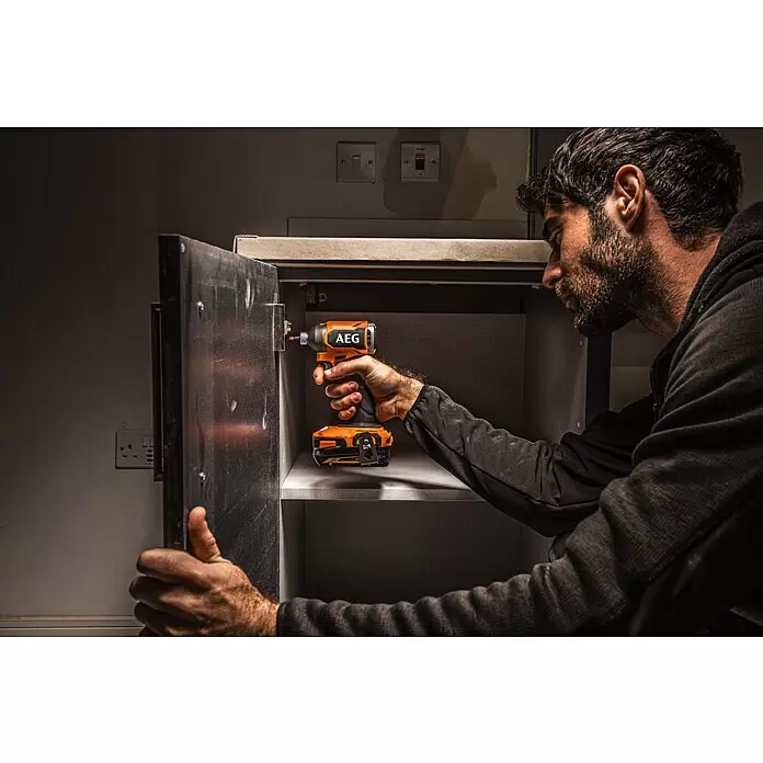 AEG Pro 18V Akku-Schlagschrauber BSS18SBL2-0 - 18 V, Ohne Akku, 200 Nm - Mann bedient einen orange-schwarzen AEG Schlagschrauber an einem Schrankscharnier.
