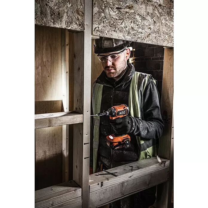 AEG Pro 18V Akku-Schlagschrauber BSS18SBL2-0 - 18 V, Ohne Akku, 200 Nm - Mann in Schutzhelm und Brille verwendet orange-schwarzen AEG Schlagschrauber an Holzrahmen.
